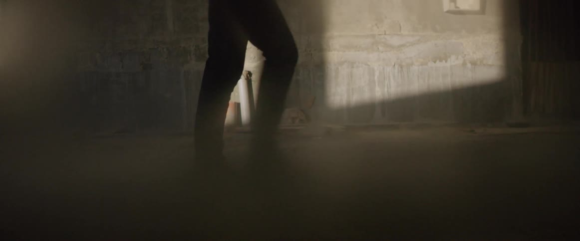 A man in a suit walks past cement walls