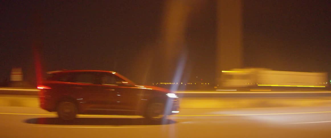 The driver gestures as he passes another on a highway at night
