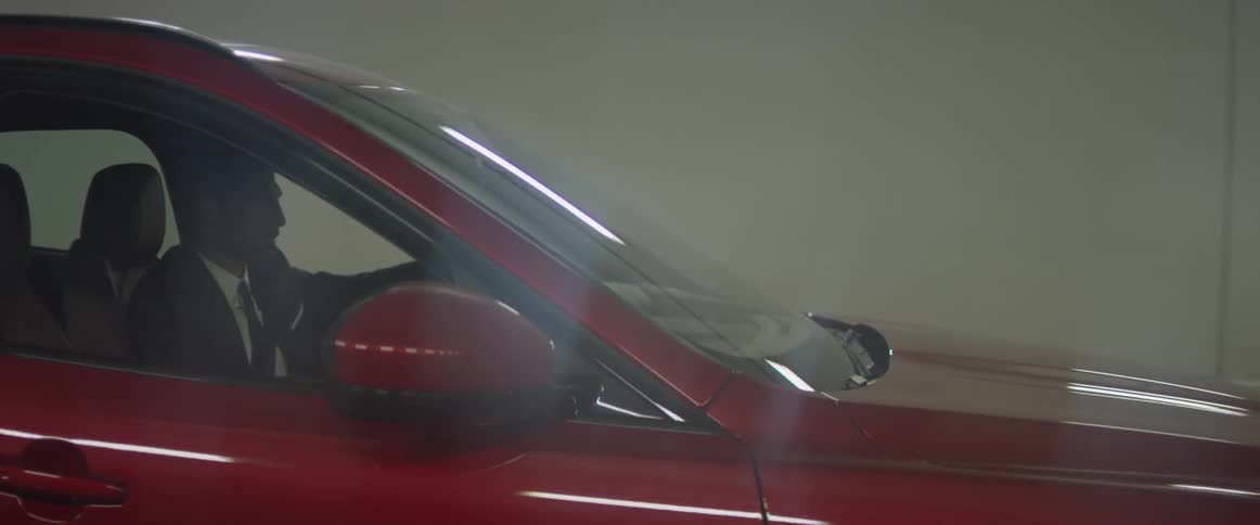 A man in a business suit is driving a luxury suv in a tunnel