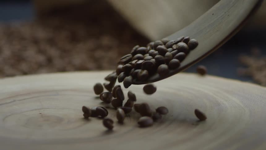 Coffee beans are spooned onto a wooden surface