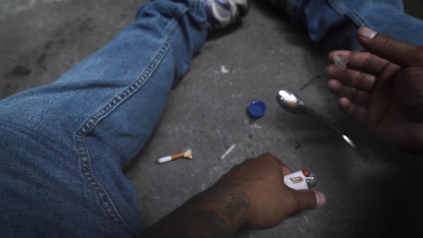 A man uses drugs on the asphalt