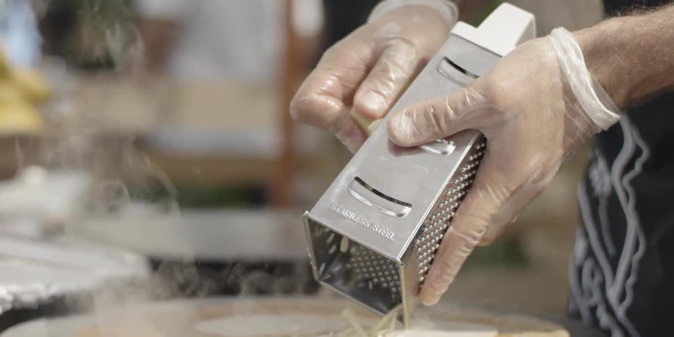 A person grates cheese onto a tortilla