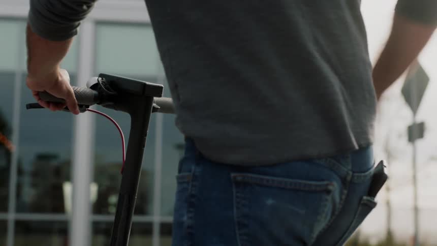 A man uses his smartphone to unlock a scooter