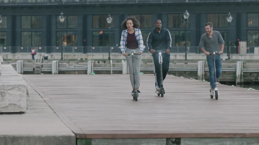 People riding scooters on a pier