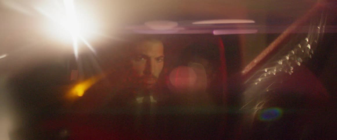 A man sitting in the car glares out the rear view mirror