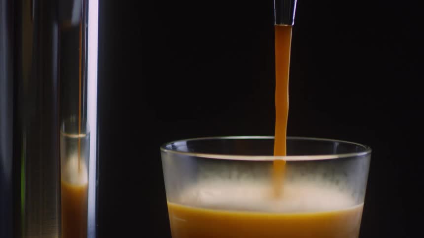 Brown liquid pours from a tap into a glass