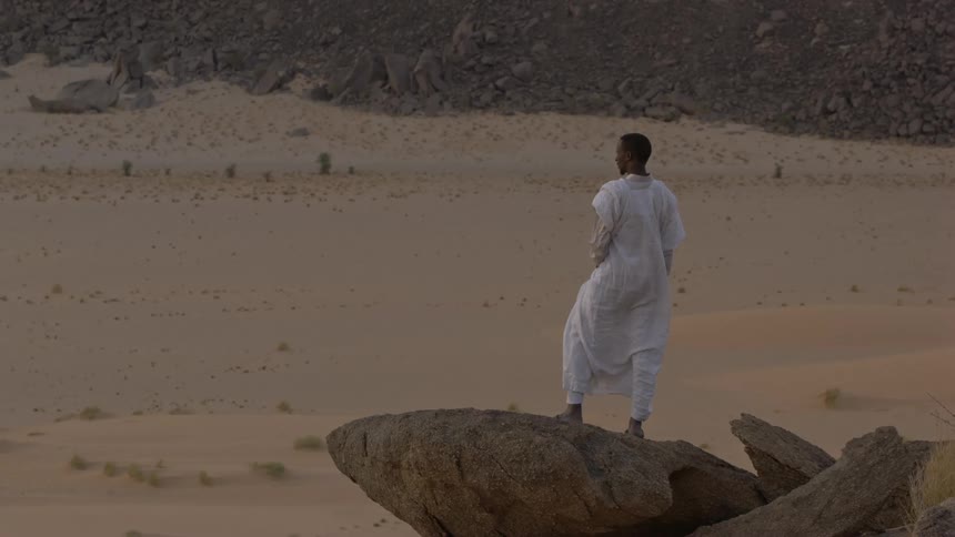 Man standing high on a rock formation looking at the land below