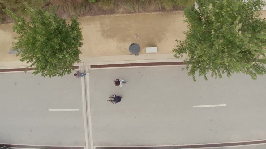 Three friends are riding scooters on a path during the day