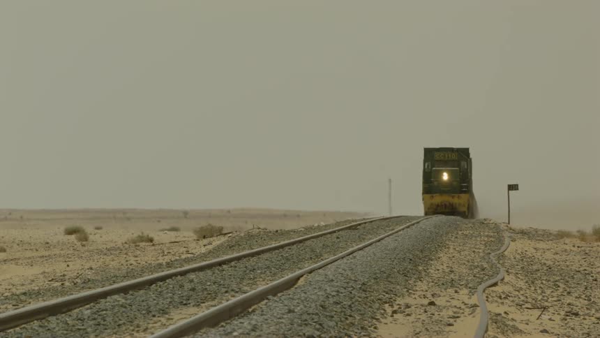A freight train travels on tracks in the desert