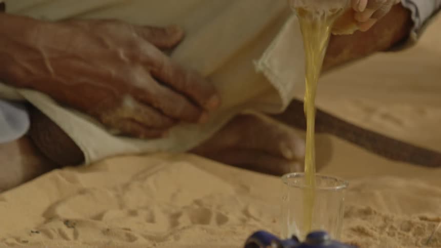 A man pours a drink back and forth between glasses
