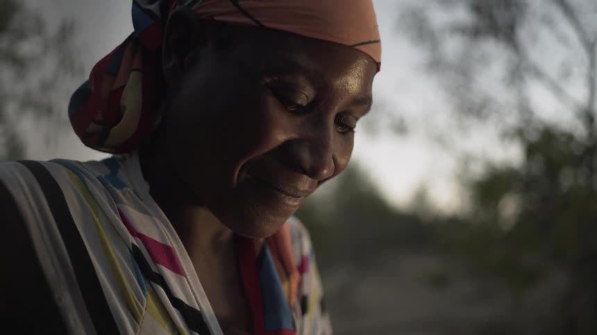 A woman smiles outside at sunset
