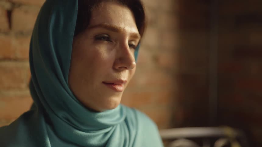 Woman in a headscarf speaks and smiles