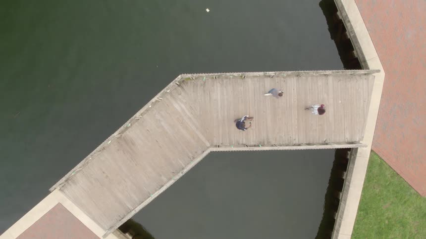 Three friends are riding scooters on a boardwalk during the day