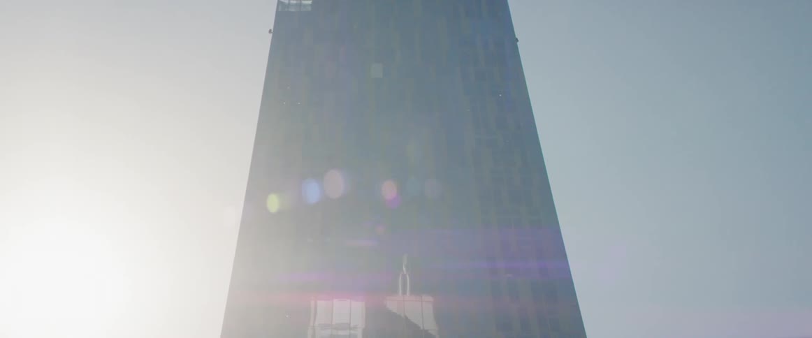 The sun shines behind a skyscraper