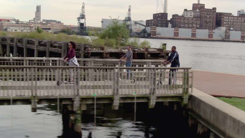 Friends ride scooters on the walkway along the harbor