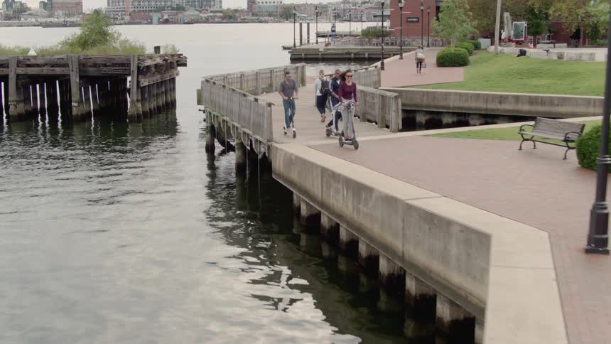 Friends ride scooters on a pier
