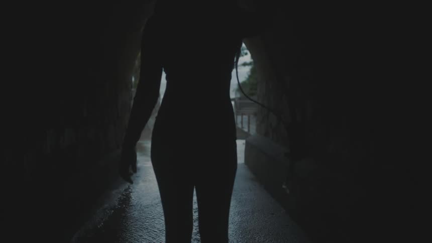 Woman walking through a dark cave towards an opening