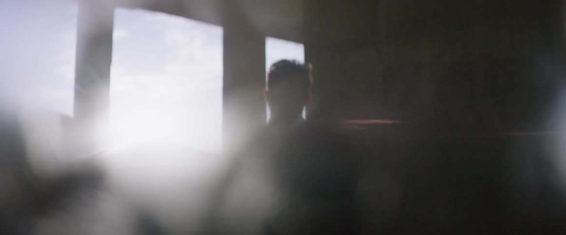 A man looks around a room with large windows