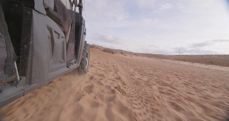 Side view of a jeep driving through the sand