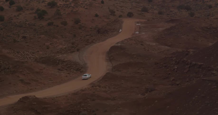 A car drives down a windy road in the desert