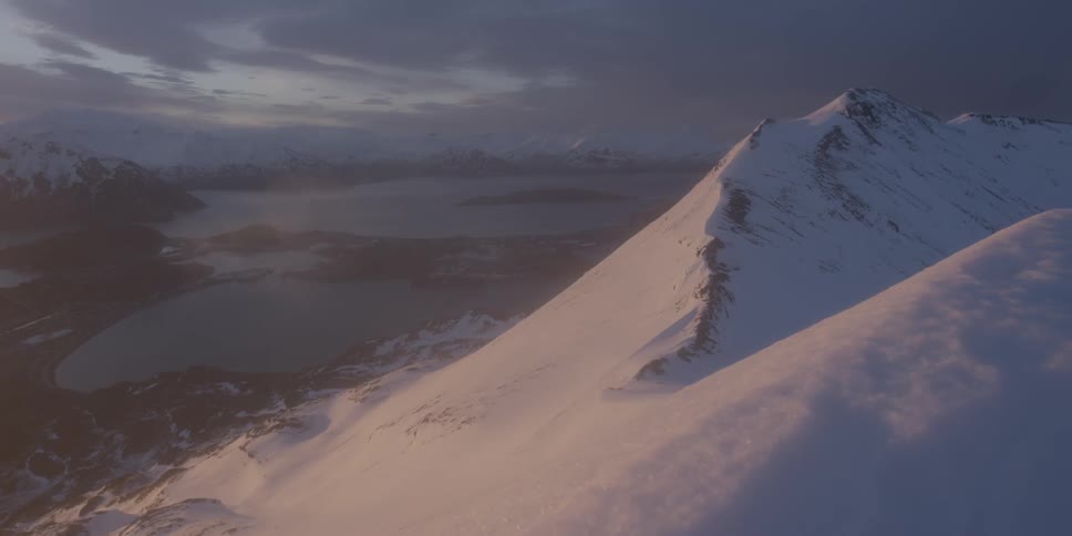 Storm clouds and fog are drifting across snow-covered mountain peaks