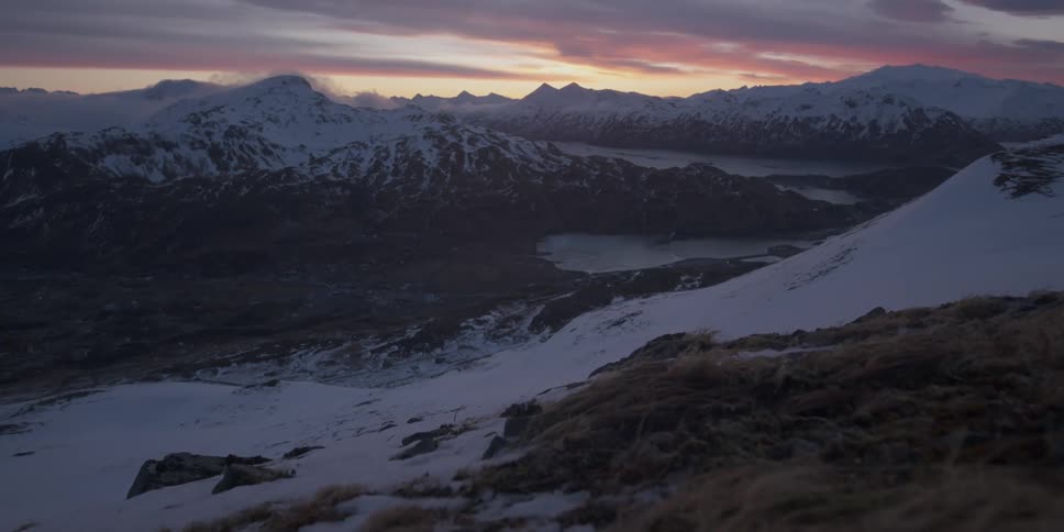 The sun sets behind snowy mountains