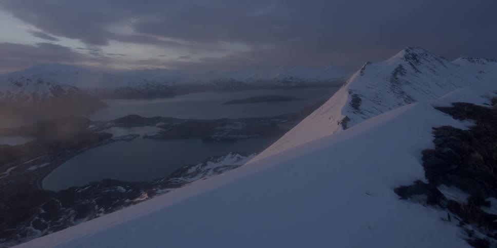 Snow covers a mountain ridge at sunset