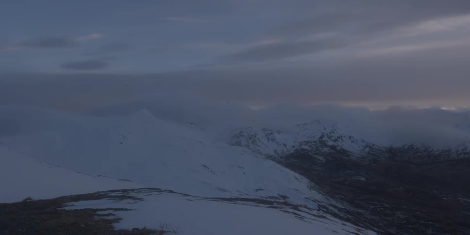 Snow covers mountains at sunset