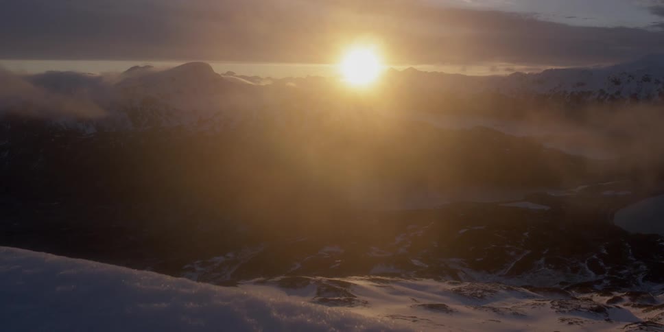 The sun sets over snowy mountain peaks