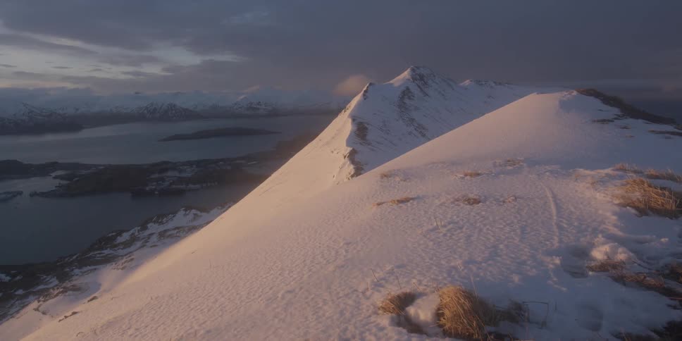 Snow covered mountain slope overlooks the water