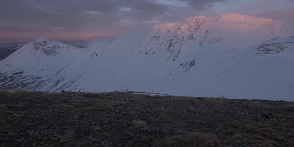 Looking at a long snow covered mountain range at dusk