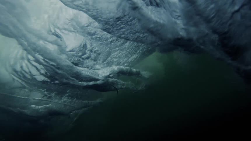 The wave crashes down sending bubbles underwater
