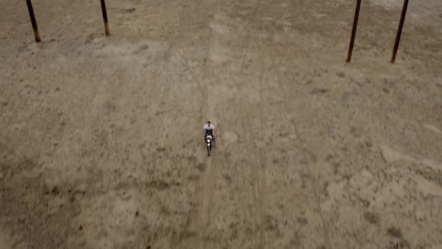 A man rides a motorcycle across a rural field