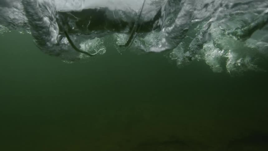 An ocean wave crashes down into the sea
