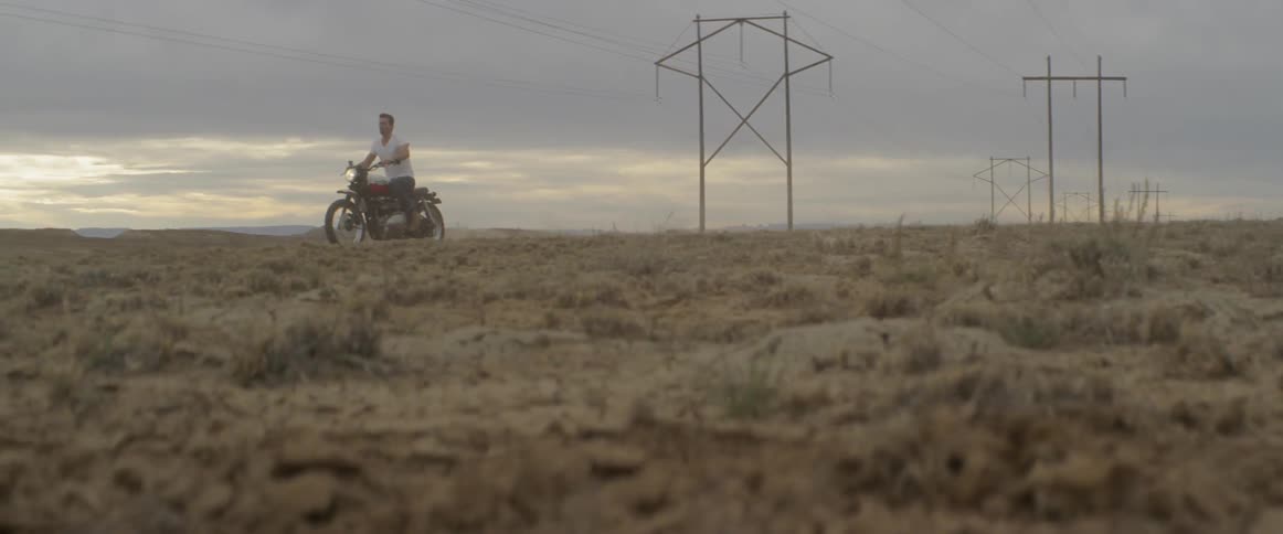 Person drives a motorcycle in a scrubby desert