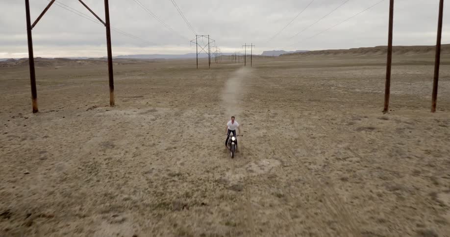 Person driving a motorcycle between power poles