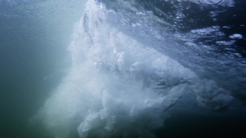 A wave is leaving a wake beneath the water as it crests and rolls