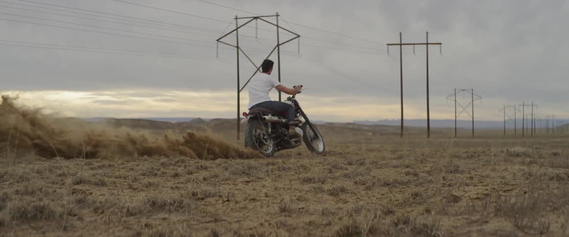 A man turns his motorcycle in the dirt shooting it everywhere