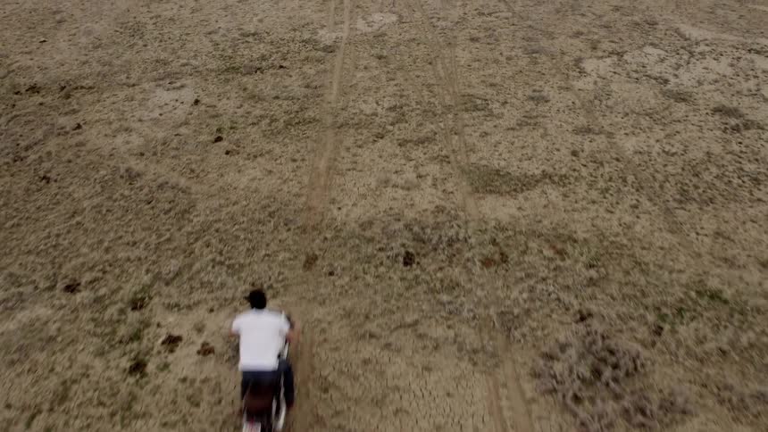 Man rides a dirt bike in a desert