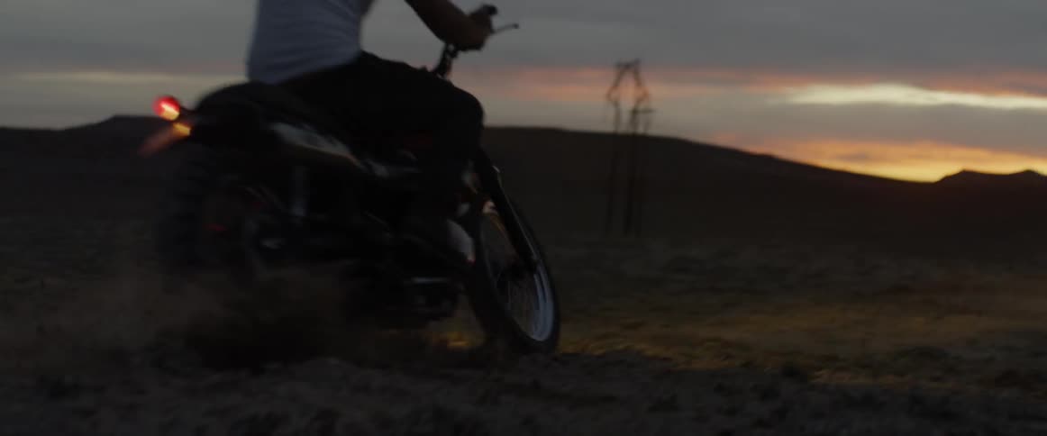 Someone is riding a bike in the desert at sunset and does a slide