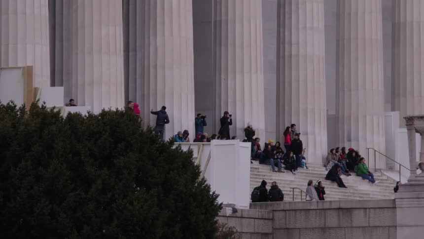 People sit on the steps of a capitol building