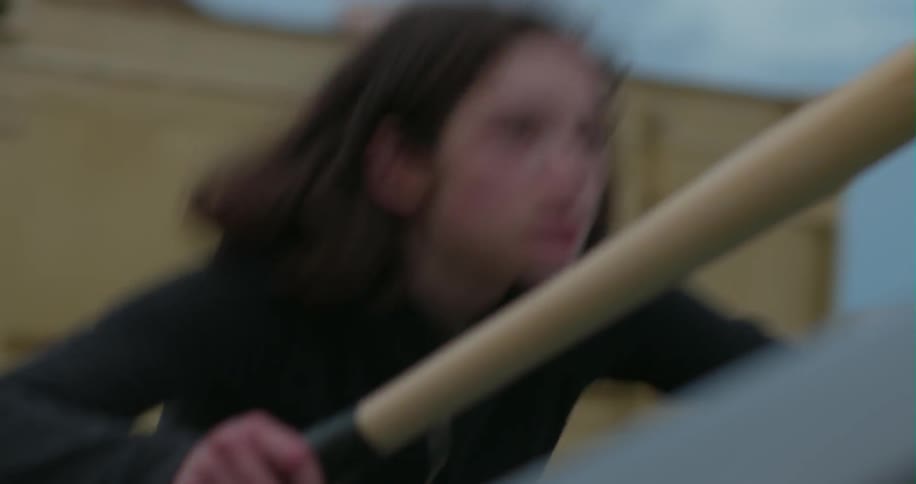 A young woman hits a car with a bat