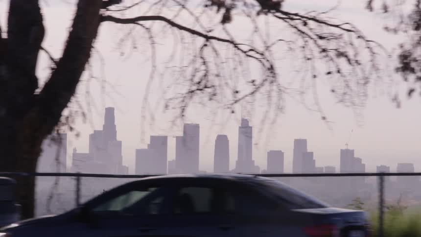 Vehicles are parked beside a road looking out onto the city skyline