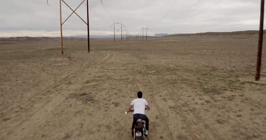 A man is riding his motorcycle under the power lines