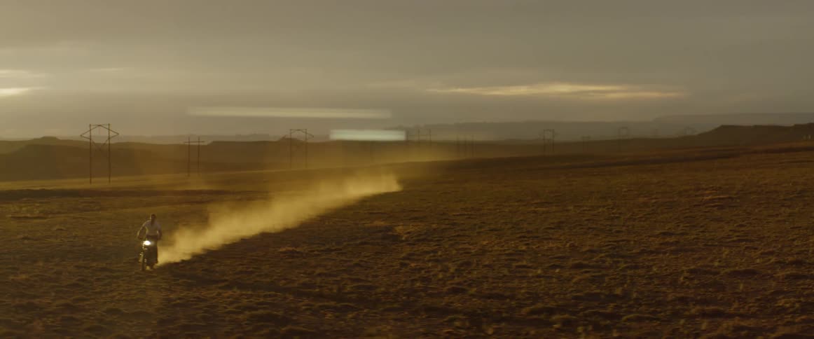 A man rides a motorcycle over dry dirt