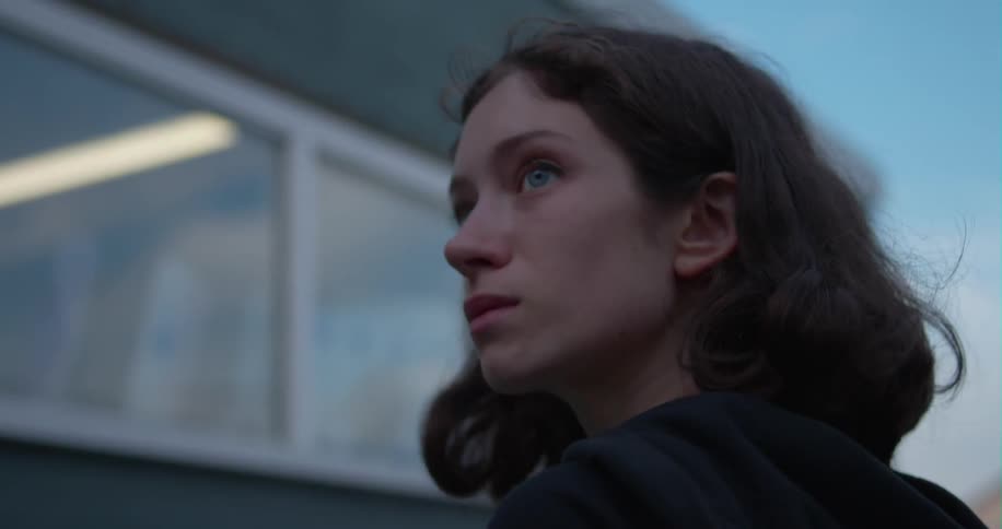 A girl with dark hair is outside and turns around to see something behind her