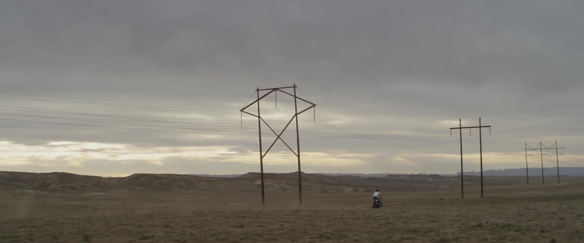 A person is riding their motorcycle near the power lines