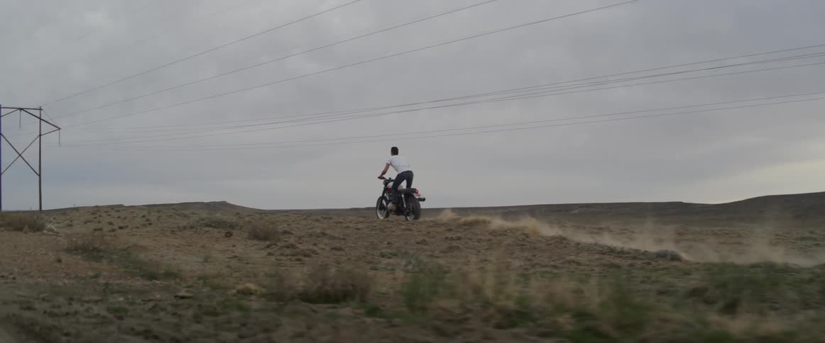 A man rides a motorcycle across a rural field