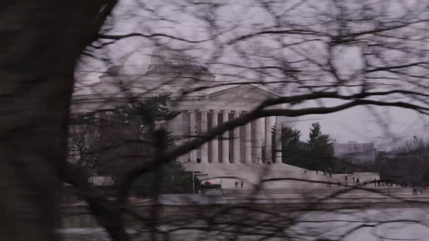 Driving past a white building with lots of pillars