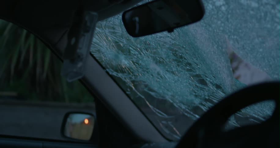 A bat is being used to break out a windshield
